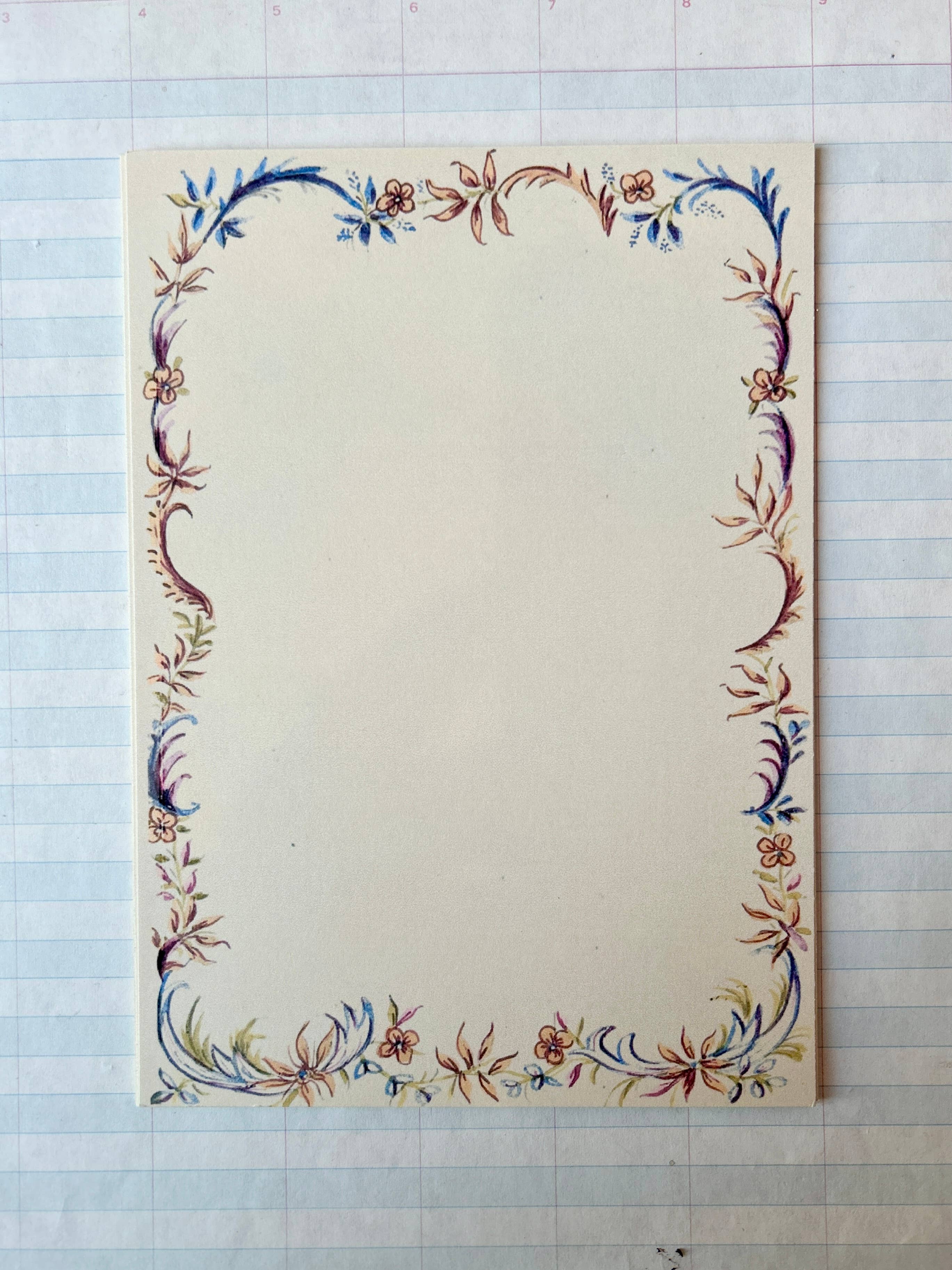 The French Menu Stationery Set II: 2 by Parcel features creamy white cardstock cards with a delicate multicolored floral border, displayed on lined paper in the background; available in a set of 8.