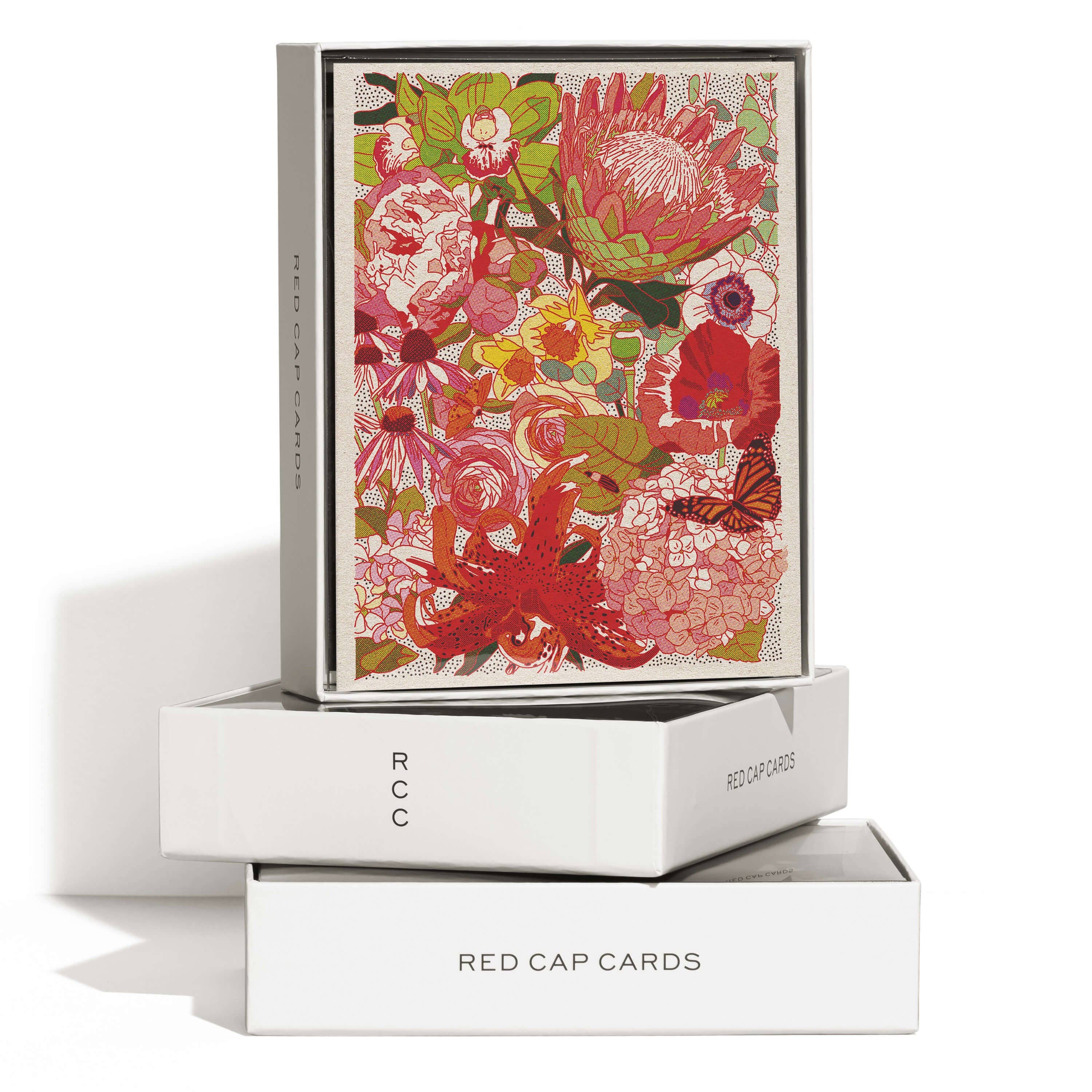 A box of Red Cap Cards’ Wild Florals greeting card: Single, showcasing a vibrant design with red, pink, and orange flowers. The open box displays the illustrated front atop two stacked white Red Cap Cards boxes.