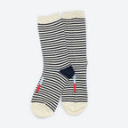 The Cole Black and White Striped Crew Socks by Hooray Sock Co. are unisex crew socks with cream toes, heels, and cuffs, plus small blue and red stripes near the bottom.