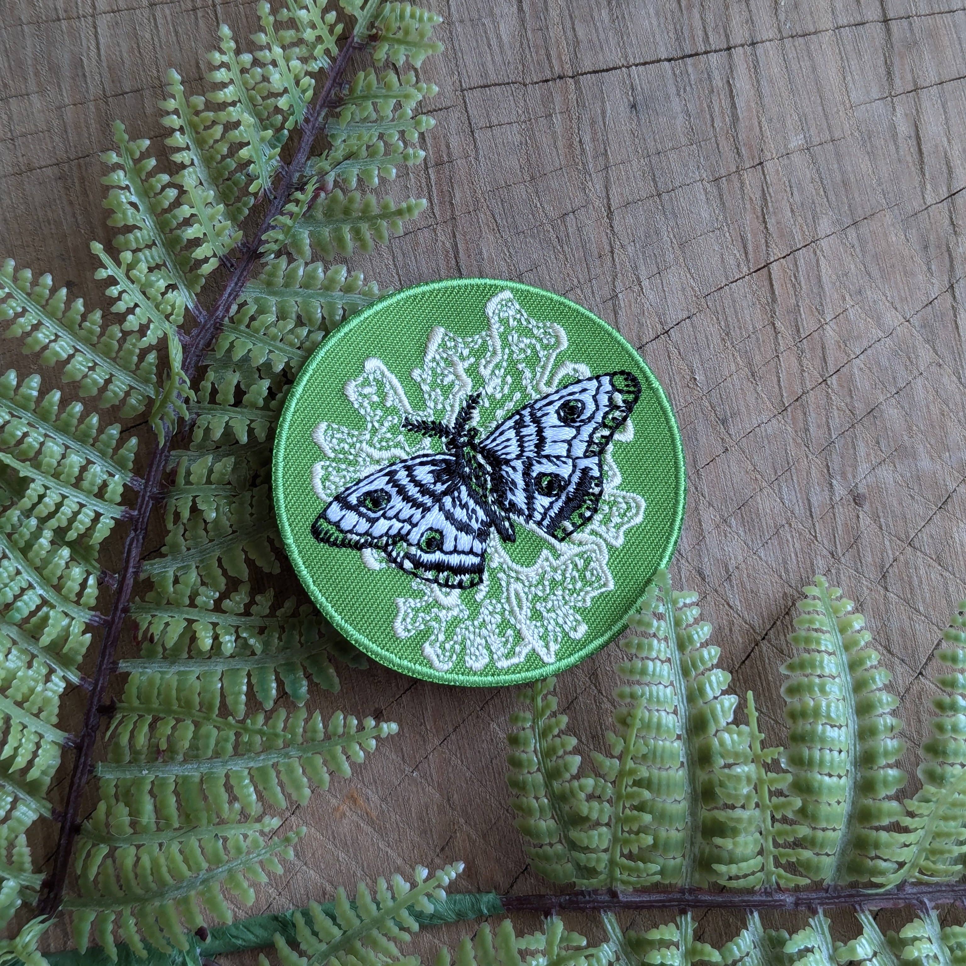 The Iron-on patch | polyphemus moth with lichen - green by ilikesara | art + goods features an embroidered moth on green, white detailing, and is perfect for adding unique insect flair to any garment.