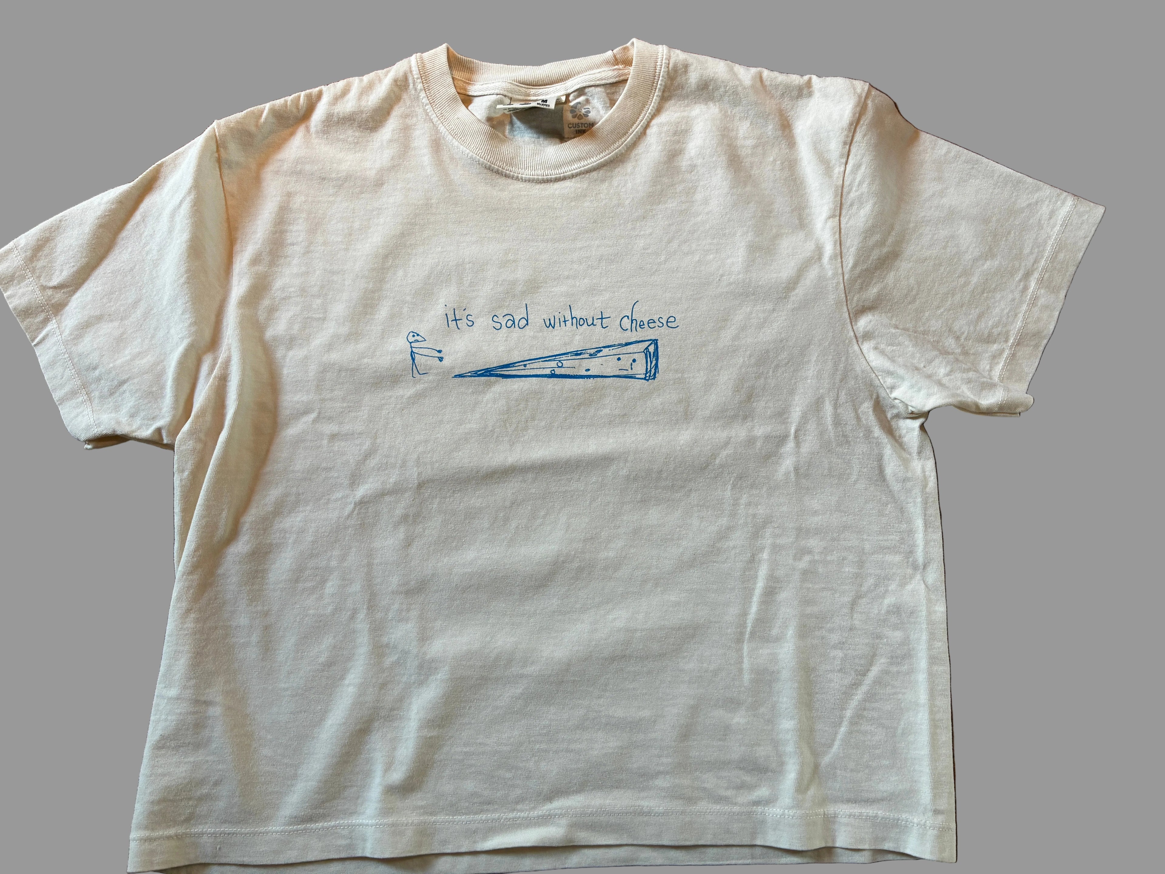 White t-shirt with blue text and graphic on a grey surface