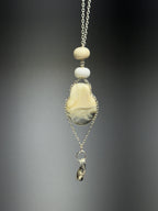 The Dove • Ash Espinoza x Thyne Studio necklace by Thyne Goods features a silver chain with cream and white beads and a marbled beige-gray pendant, crafted from recycled sterling silver, finished with an irregular metallic charm.