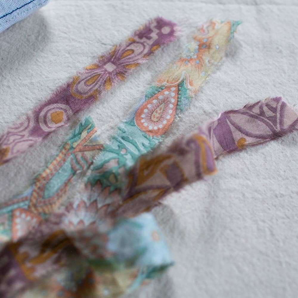 The Skippy Cotton Flying Kite - Cotton & Lavender filled Ornament features pastel-colored, patterned organic cotton fabric with paisley and floral designs, beautifully displayed on a textured white surface.