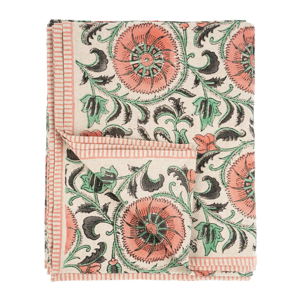 The Botanique Block Print Tablecloth Pink by Indaba Trading is crafted from a linen-cotton blend with a hand block floral print in coral, green, and black on cream, finished with thin coral striped borders and a turned-up corner to show the reverse.