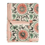 The Botanique Block Print Tablecloth Pink by Indaba Trading is crafted from a linen-cotton blend with a hand block floral print in coral, green, and black on cream, finished with thin coral striped borders and a turned-up corner to show the reverse.