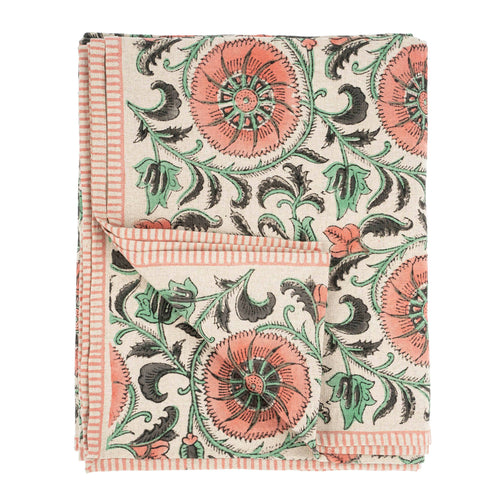 The Botanique Block Print Tablecloth Pink by Indaba Trading is crafted from a linen-cotton blend with a hand block floral print in coral, green, and black on cream, finished with thin coral striped borders and a turned-up corner to show the reverse.