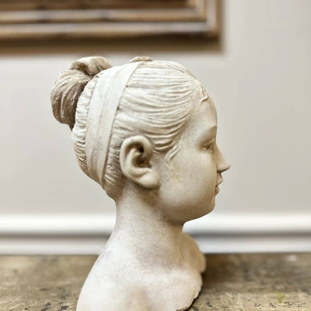 The Cement Girl Statue by Vagabond Vintage is a hand-cast cement bust of a young woman in profile, featuring a bun and headband—an elegant decor accent for your garden or neutral settings.