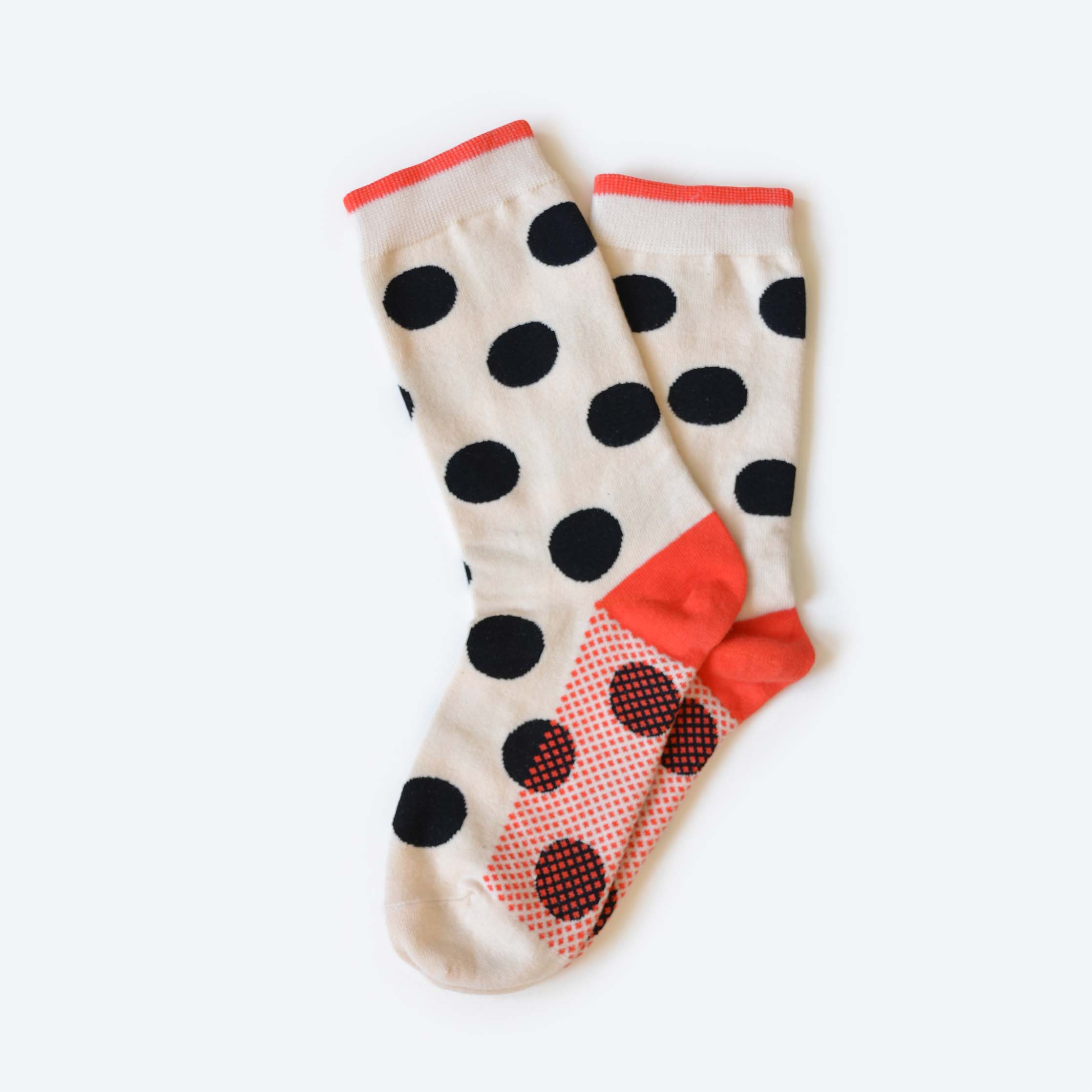 The Hooray Sock Co. Valley Sock is a unisex crew sock featuring a cream base with bold black polka dots, red cuffs, heels, and toes, plus small red dots near the toe. Made from soft cotton spandex and shown overlapping on a white background.