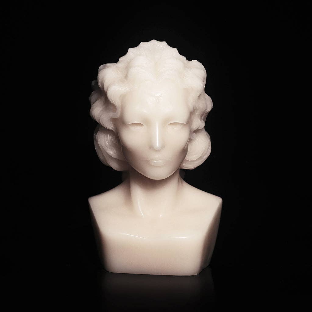 WEEPING BUST by Heretic Parfum is a smooth, white marble candle shaped like an abstract person with wavy hair and minimal features, creating an elegant look against a black background.