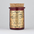 The Apothecary / Love Potion / Valentine Candle by North Ave Candles is a red glass jar candle with a cork lid. Vintage label features neroli, violet, passionfruit, ginger, lemon, and thyme fragrance and a 35-hour burn time.