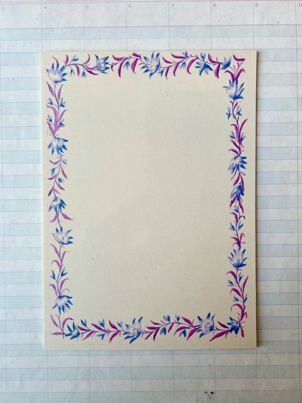 The Parcel French Menu Stationery Set II: 2 features creamy white cardstock with pink and blue hand-painted floral borders, shown on lined graph paper. Sold as a set of 8 printed cards.