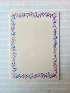 The Parcel French Menu Stationery Set II: 2 features creamy white cardstock with pink and blue hand-painted floral borders, shown on lined graph paper. Sold as a set of 8 printed cards.
