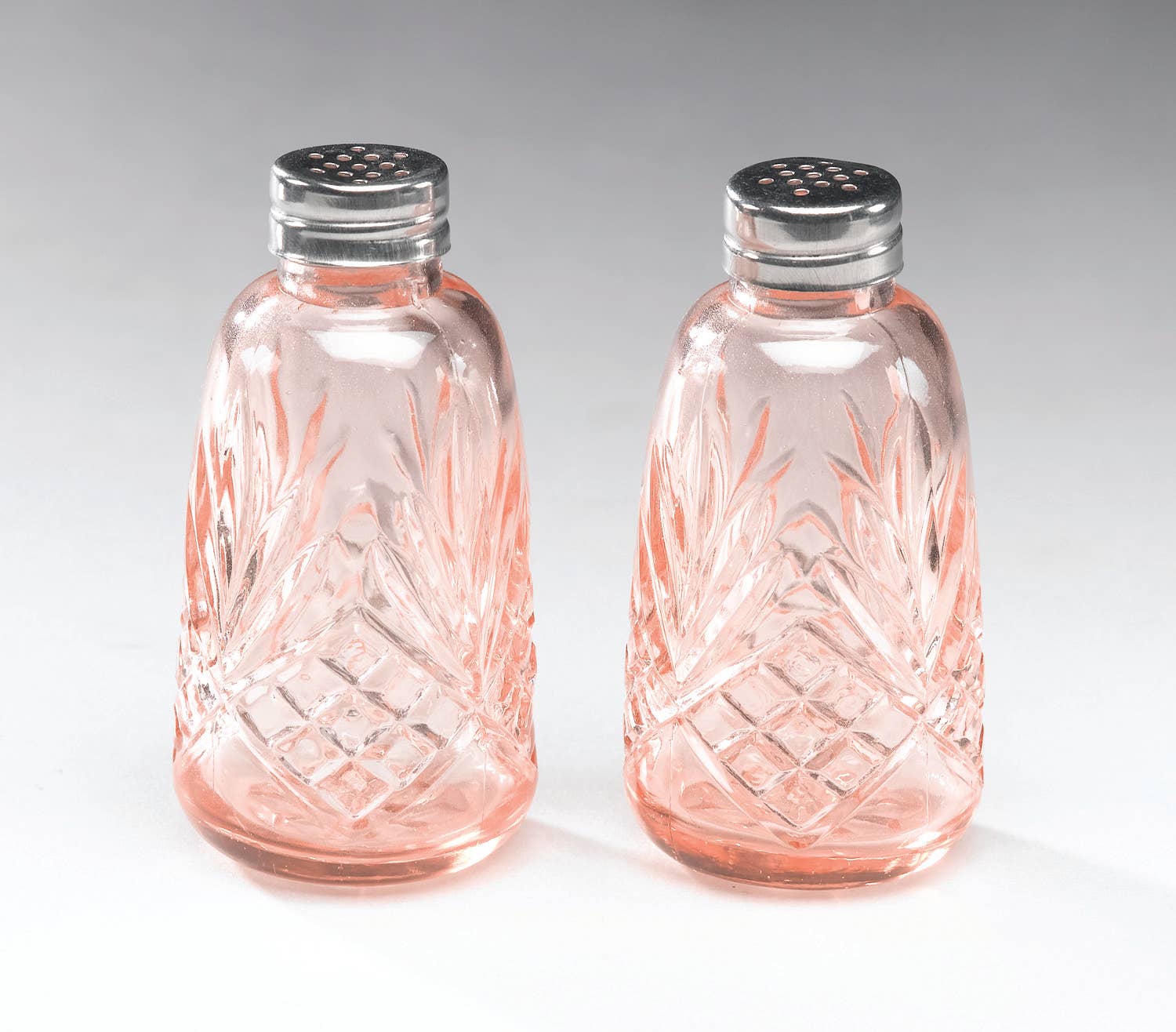 The AA Importing Depression Glass Salt & Pepper Set in Pink features vintage-style shakers with silver lids and a diamond-leaf cut pattern, displayed side by side on a light gray background—ideal for collectors.