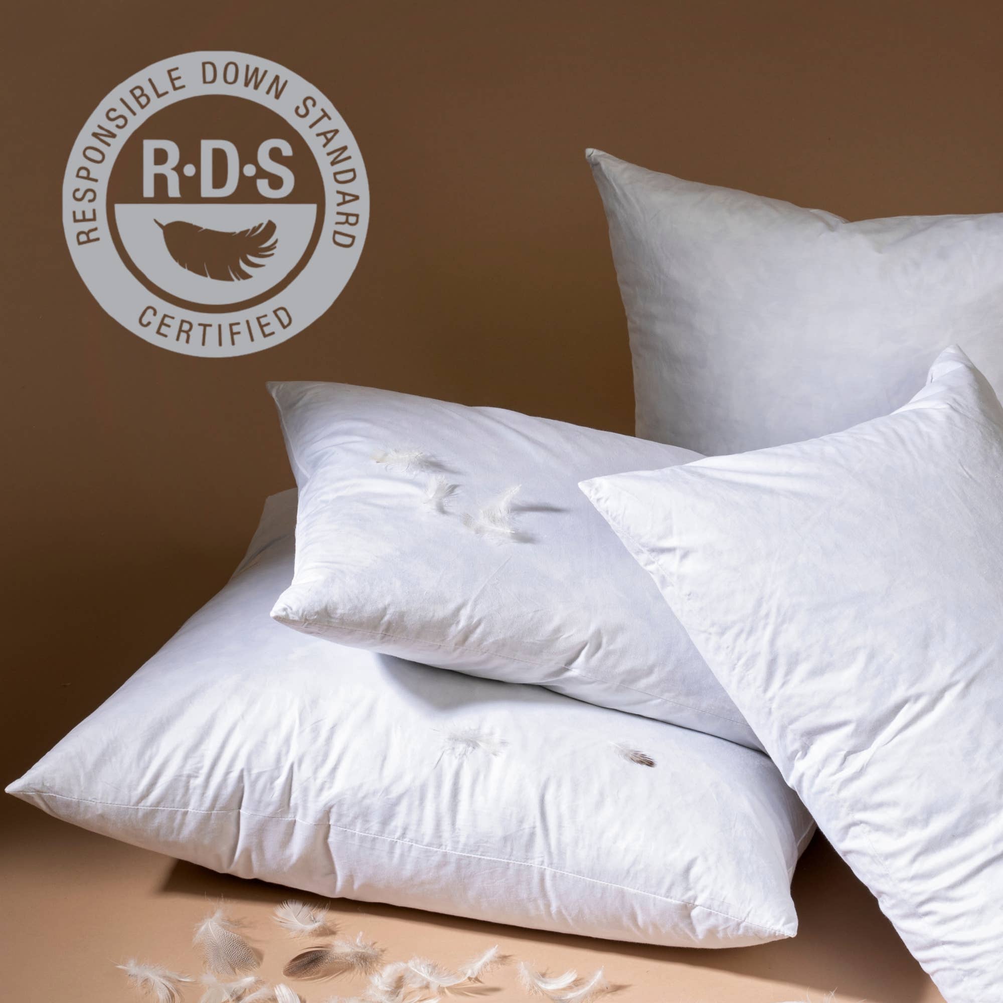 Four white Indaba Trading 24x24 Lina Linen Pillow Avocado: Cover with Filler are stacked against a neutral brown background. The upper left shows the Responsible Down Standard (RDS) Certified logo to highlight sustainable sourcing.
