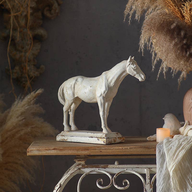 The Rustic Horse Sculpture by Vagabond Vintage adds antique charm to a wooden table, accented with dried pampas grass, a candle, and fabric in cozy farmhouse decor.