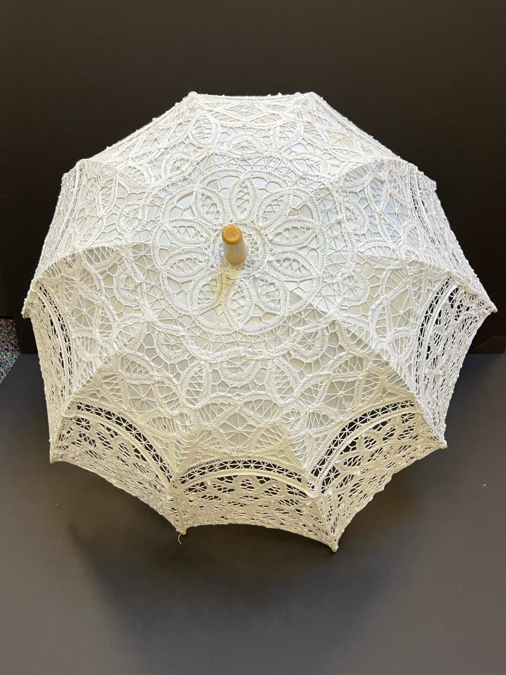 The Parasol - White by Peking Handicraft features intricate lace and a wooden handle, displayed open against a dark background—an elegant Victorian-inspired accessory for any occasion.