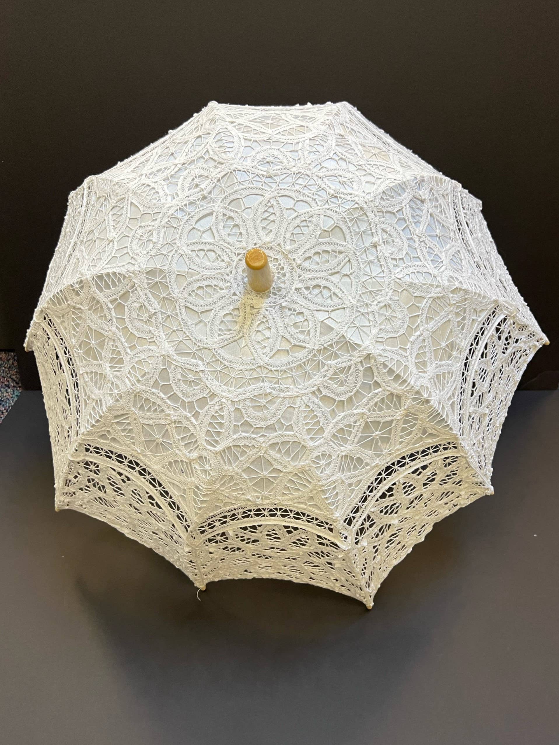 The Parasol - White by Peking Handicraft features intricate lace and a wooden handle, displayed open against a dark background—an elegant Victorian-inspired accessory for any occasion.