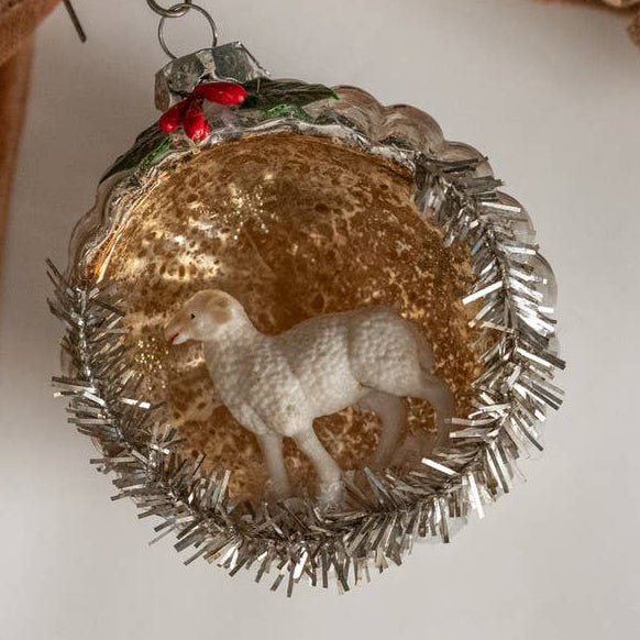 Add a whimsical touch to your holiday decor with the SHEEP SCENE ORNAMENT by Ragon House, charmingly displayed on a festive ribbon.