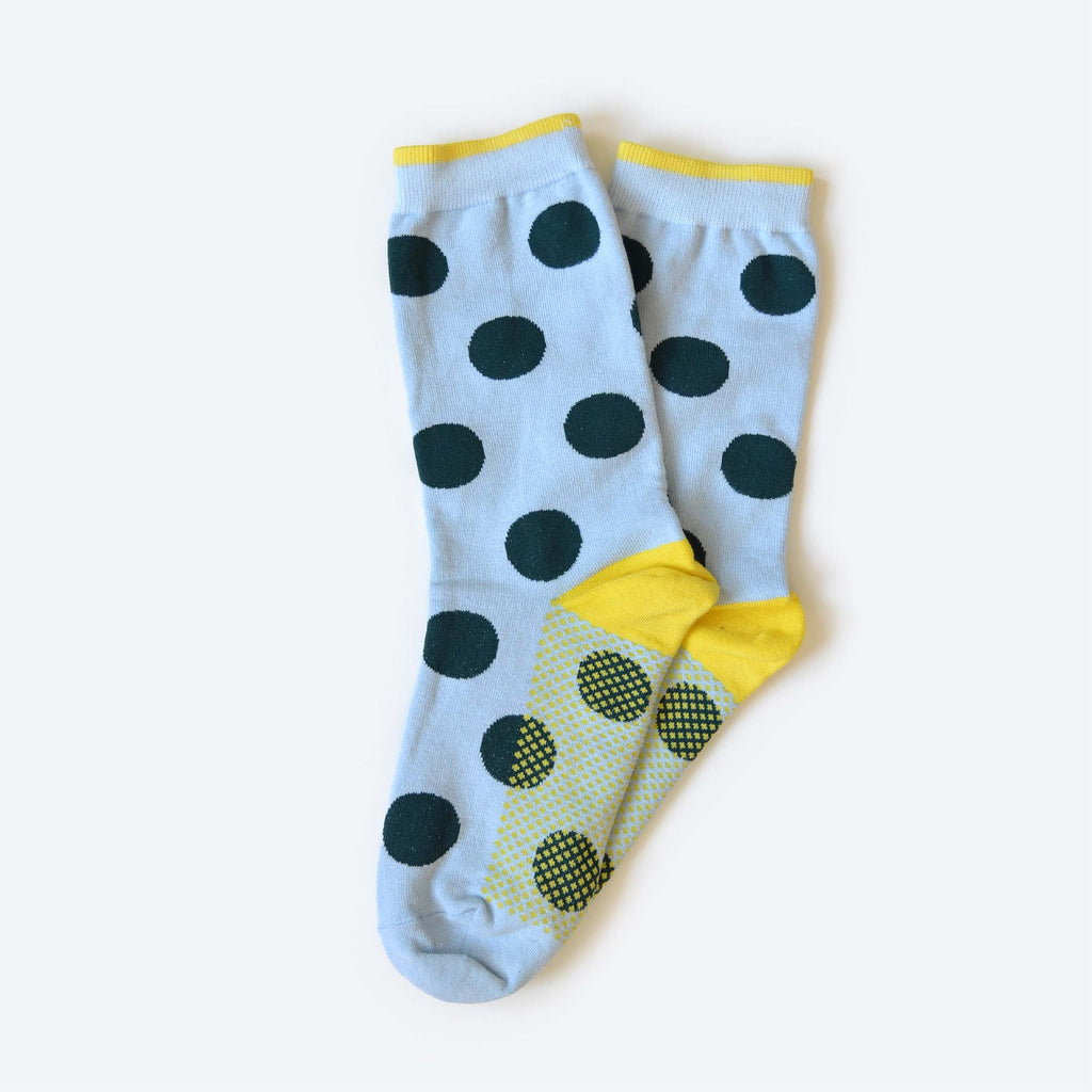 The Clipper Sock by Hooray Sock Co. is a unisex crew-length pair, mint with large dark blue polkadots and yellow accents on the cuffs, heels, and toes, shown overlapping on a light background.