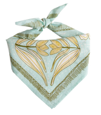 The No. 012 Eliza Bandana by Handker Bandanas features a light blue floral design with gold and olive green abstract accents, hand screen-printed on premium cotton and tied in a knot against a white background.