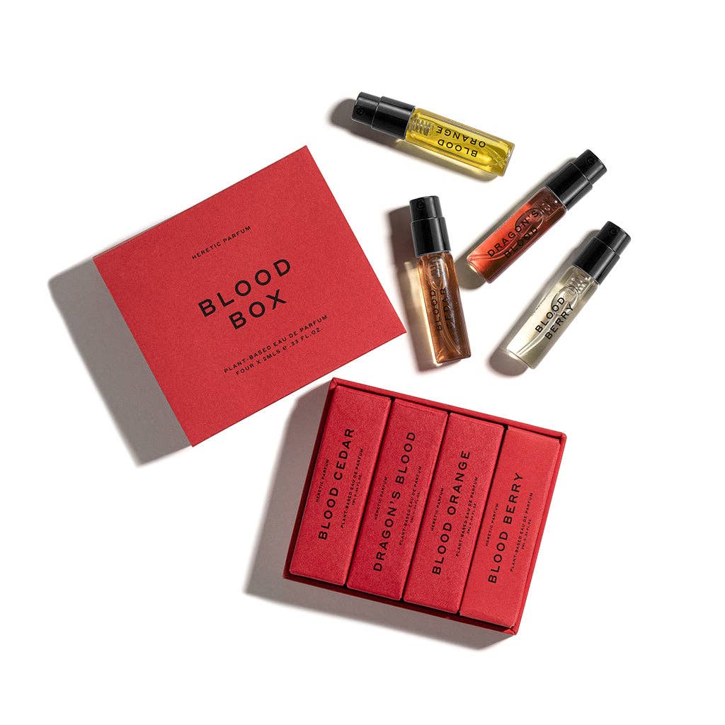 THE BLOOD BOX by Heretic Parfum: a limited edition fragrance set featuring four blood-inspired scent vials—Blood Cedar, Dragons Blood, Blood Orange, and Blood Berry—displayed in and around a bold red box against a white background.