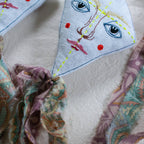The Skippy Cotton Flying Kite is a cotton and lavender-filled ornament with an embroidered face, yellow center stitching, and colorful tails—ideal as a unique gift topper or whimsical scented sachet.