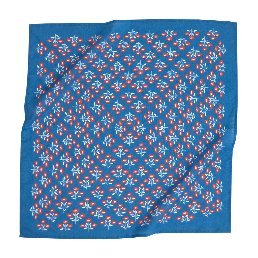 The No. 075 Juliet Bandana by Handker Bandanas is a 22x22-inch premium blue cotton bandana, hand screen-printed with small red and white flowers and green leaves. The scarf has a slightly wrinkled appearance.