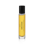 A clear glass bottle of Heretic Parfum SMUDGE: 15ML with yellow liquid and a black cap features minimalist design, suggesting notes of juniper and frankincense, displayed on a white background.