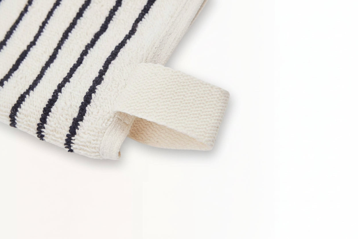 Close-up of The Loomia’s Turkish Cotton Striped Terry Towel: Bath Sheet featuring quick-drying Turkish cotton, black horizontal stripes, and a corner fabric loop, displayed on a plain white surface.