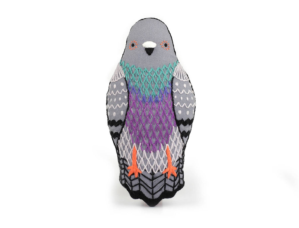 Stuffed pigeon from a Pigeon - Embroidery Kit, featuring gray, teal, and purple embroidered plumage and orange feet.