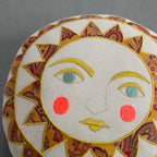 The Skippy Cotton Bright Neon Sun Pillow is a handmade, cotton-filled round cushion featuring an embroidered sun face with yellow and orange rays, blue eyes, yellow lips, and red cheeks—a vibrant accent for whimsical decor.