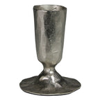 The HomArt Jon Candlestick in nickel features a rough, silver finish with a wide, uneven base and hammered surface, creating the look of a handcrafted piece with rustic charm.