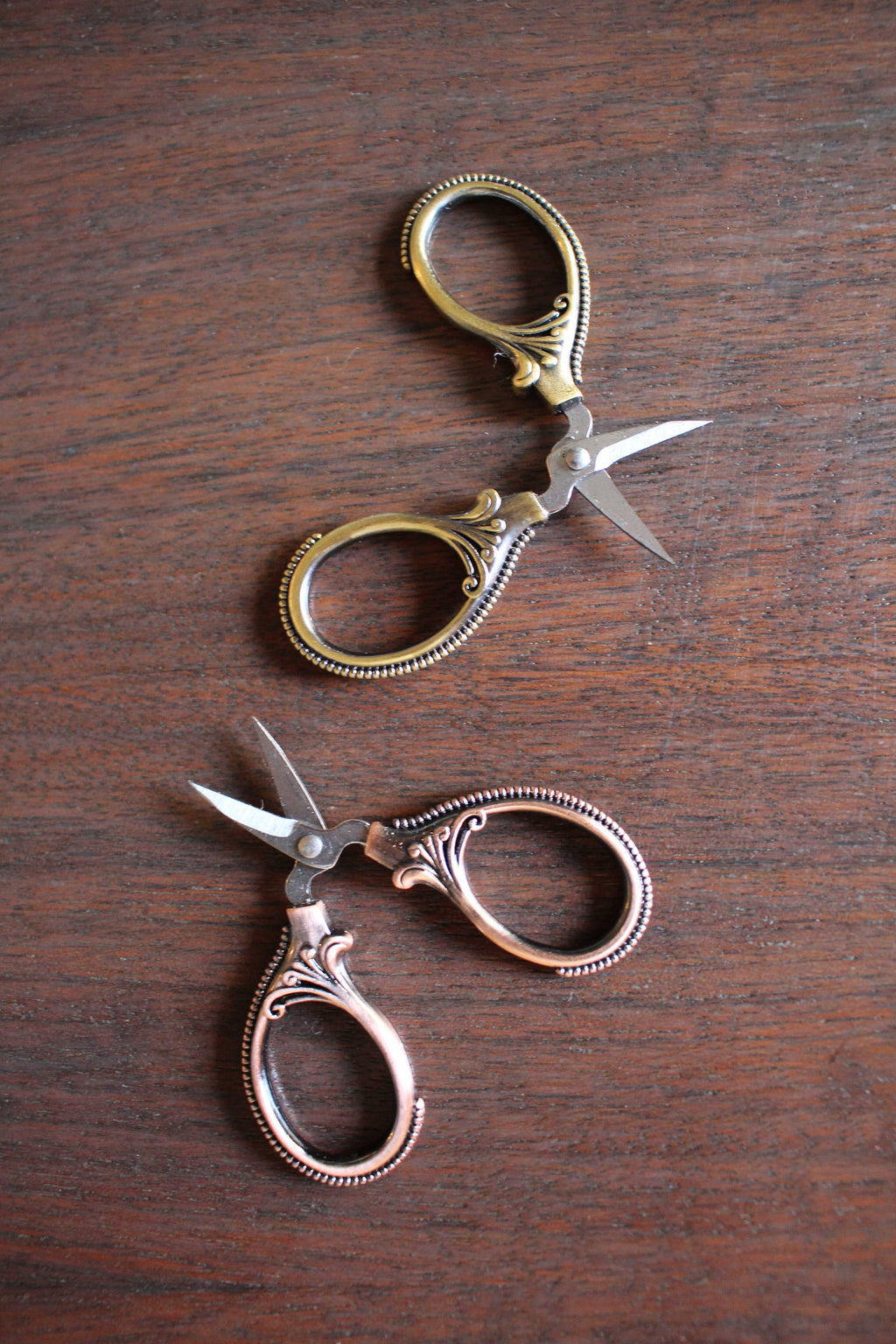 The Mini Embroidery Scissors: Antique Gold by NNK Press feature ornate handles and sharp stainless steel blades. These compact sewing snips are perfect travel notions for any sewing enthusiast and sit elegantly on any work surface.