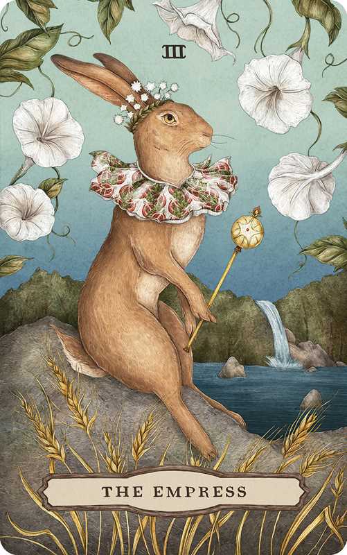 A majestic rabbit adorned with a crown and ruffled collar clasps a scepter amid white flowers, wheat, and a cascading waterfall on this nature-inspired tarot card from Tarot of the Woodland Wardens by Jessica Roux (Simon & Schuster). The card features The Empress and the Roman numeral III.