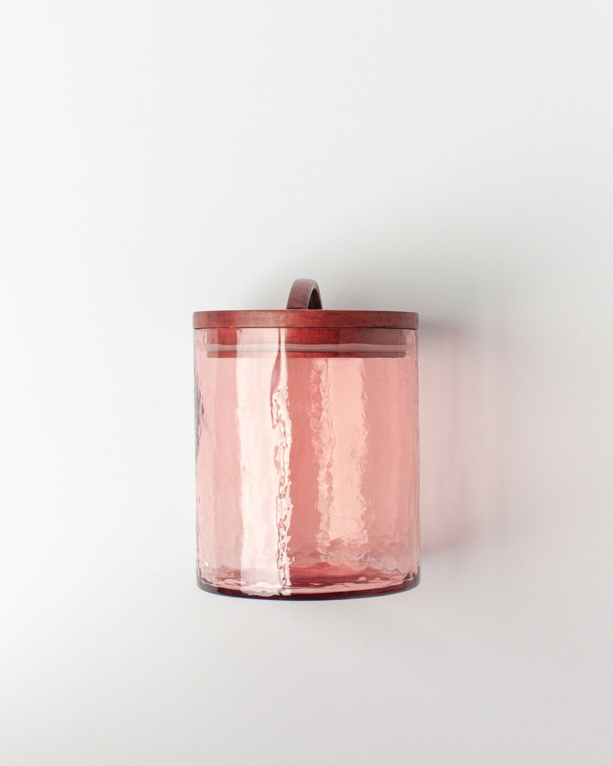 The Handblown Hammered Glass Canisters: Blush / Small by Creative Women features translucent pink recycled glass with a textured surface and a hand-carved wooden lid on a plain white background.