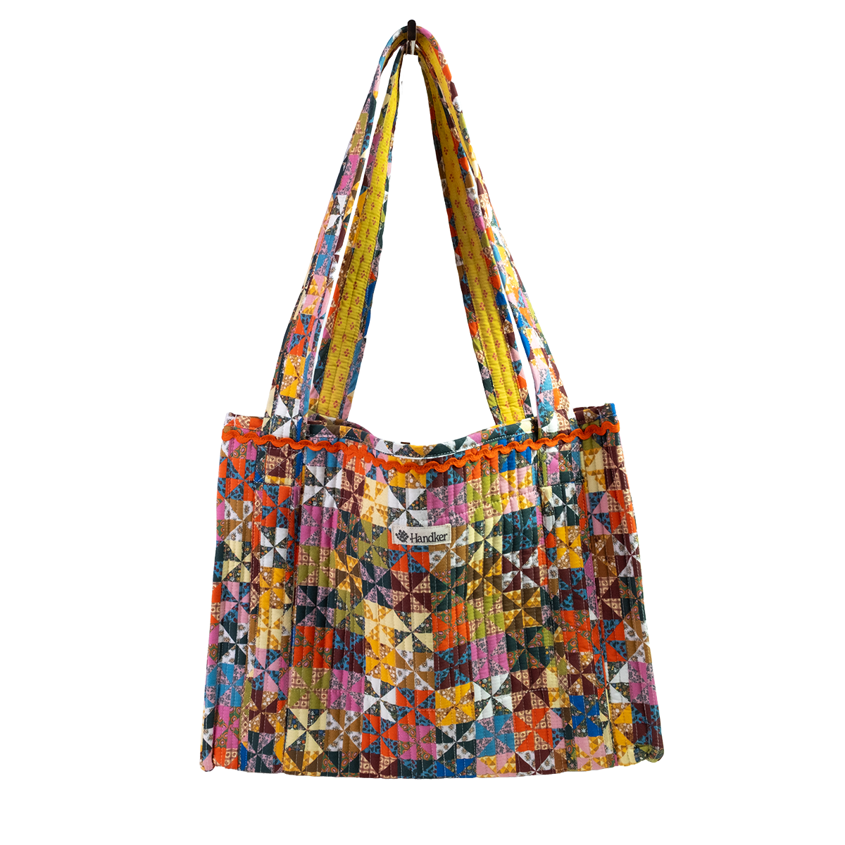 The Calico Quilted Tote by Handker Bandanas features a geometric pinwheel quilt pattern in bright colors, two shoulder straps, and a small kinder label on the front against a plain white background.