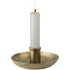 A lit white candle stands in the HomArt Tanta Taper Holder, crafted from brass-plated aluminum, featuring a simple round base against a plain white background.